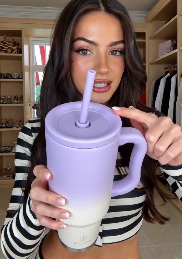 A creator pointing at the lid and straw of a lilac tumbler