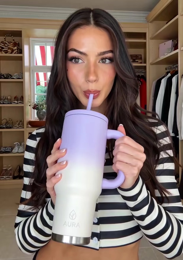 A creator sipping from a lilac tumbler through its straw